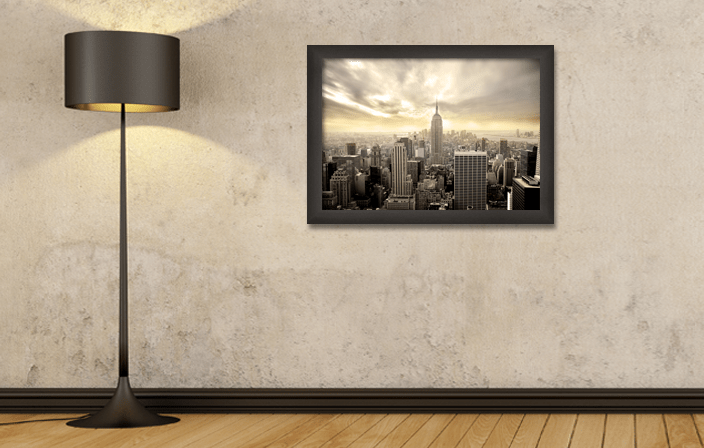 Aluminium Poster Frame Sideloader Modern AC40 in black color, with poster of Manhattan, placed in interior with standing lamp. Picture frame producer Debex Suisse.
