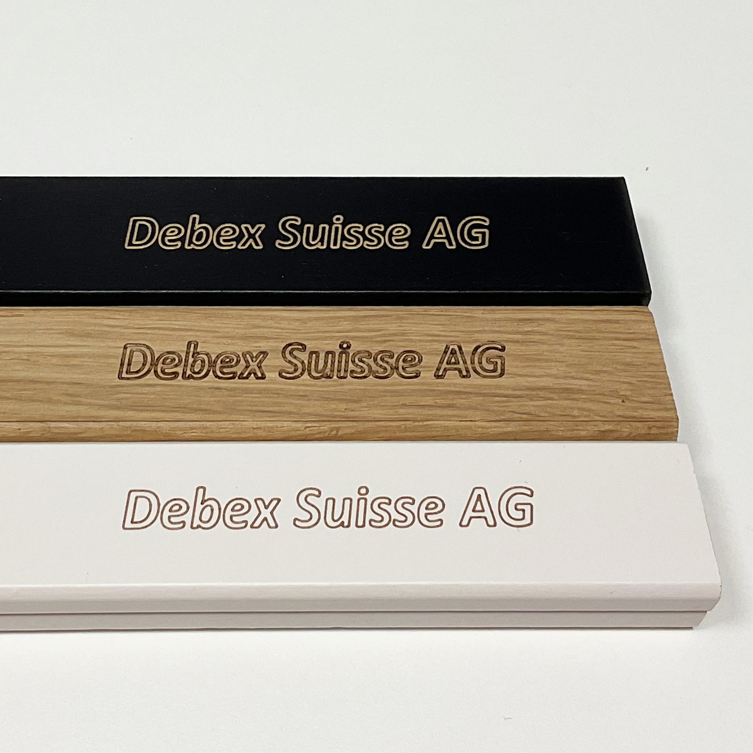 Custom engraved wooden bars in black, natural oak, and white with Debex Suisse AG logo